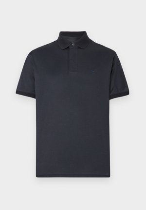 Tmavomodré polo tričko z hladkej bavlny. Má klasický golier, krátke rukávy a jemné logo na hrudi.