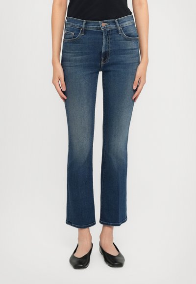 Jeans dżinsowe w ciemnoniebieskim kolorze o prostym kroju nogawek, z delikatnym przetarciem, pięcioma kieszeniami i klasycznym zapięciem na guzik w pasie.