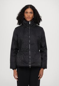 Black puffer jacket with a high collar, featuring an all-over text pattern. The design includes a front zipper and elastic cuffs.