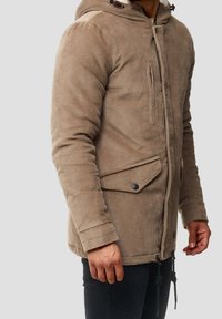 Beige Cordjacke aus Kord, mit Kapuze, durchgehendem Reißverschluss, zwei aufgesetzten Taschen mit Knöpfen und verstellbaren Kordelzügen am Saum.