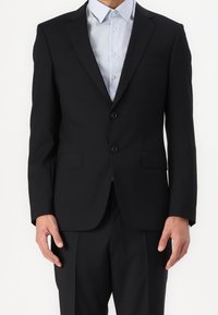 Czarna marynarka w slim fit, z dwoma guzikami, wyłogami oraz bocznymi kieszeniami, w zestawieniu z jasnoniebieską koszulą w paski. Gładka tekstura, formalny design.