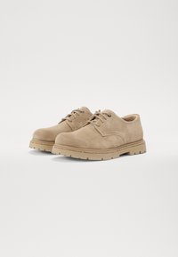 Beige semskede sko med avrundet tå, snøring, og robust gummisåle med subtile tekstur- og sømdetaljer.