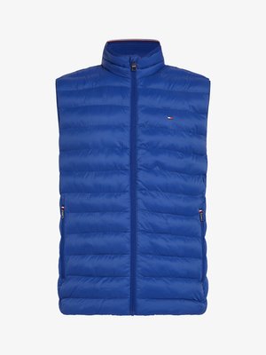 Chaleco acolchado sin mangas de color azul con cuello alto, cierre frontal de cremallera y bolsillos laterales. Presenta secciones acolchadas horizontales y un detalle de logo.