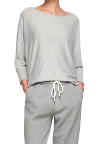 Světlé šedé tričko s dlouhým rukávem a širokým výstřihem, doplněné o odpovídající kalhoty s texturou a šňůrkou. Měkký materiál, volný střih.