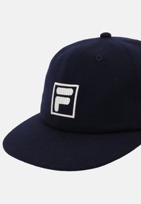 Gorra azul marino hecha de fieltro, con un logo blanco cuadrado que tiene una 'F' en el centro. Visera curvada con detalles de costura.
