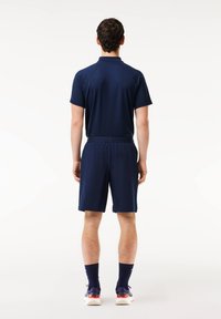 Navy athletic outfit consisting of a short-sleeve polo shirt and knee-length shorts, made of smooth fabric with elastic waistband.