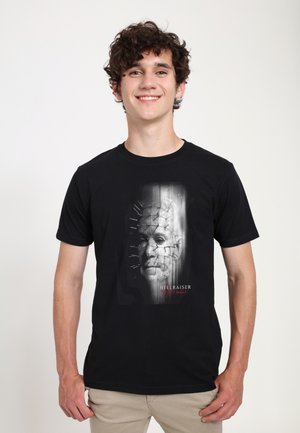 Sort bomulds T-shirt med et grafisk print af et ansigt med nåle og en mørk baggrund; teksten nedenfor lyder "HELLRAISER."