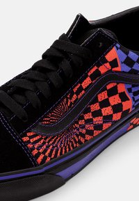 Adidași negri din suede cu modele vibrante în carouri roșii și albastre, cu șireturi negre și accente violet pe talpă și cusături.