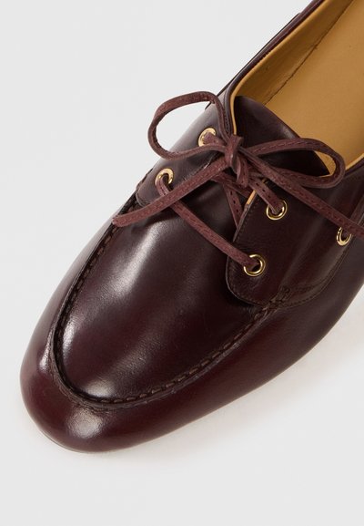 Pantofi din piele burgundă închisă cu o finisare netedă, având ochiuri de metal aurii, vârf rotund și un design de șireturile cu șireturi maro.
