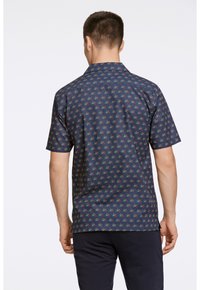 Korte mouwen overhemd van marineblauwe stof met een herhalend patroon van kleurrijke fietsen. Glad oppervlak met een klassieke kraagontwerp.