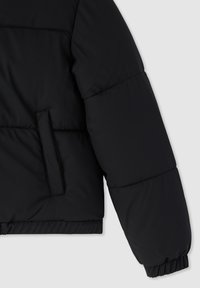 Czarna, ocieplana kurtka z rękawem i boczną kieszenią oraz elastycznym mankietem, na jasnoszarym tle.