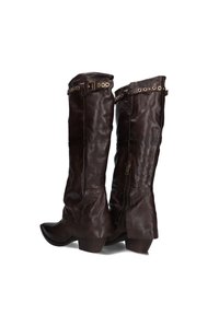 Bruine leren kniehoge laarzen met een slouchy ontwerp, decoratieve metalen hardware en een spitse neus; zijn voorzien van zijritsen voor eenvoudig aan- en uittrekken.