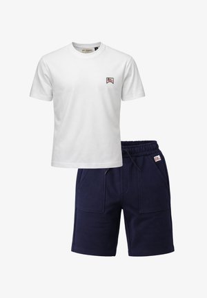 Maglietta bianca a maniche corte con scollo rotondo, piccolo logo sul petto e pantaloncini blu navy con coulisse, tasche frontali e patch con logo abbinato.