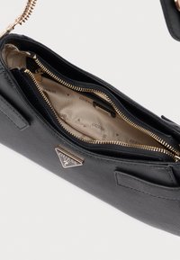 Czarna syntetyczna torebka z zamkiem błyskawicznym wewnątrz, złotymi okuciami i tabliczką z logo. Charakteryzuje się teksturowaną powierzchnią na zewnątrz oraz beżową podszewką.