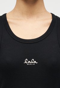 Μαύρο ριμπ τοπ με στρογγυλή λαιμόκοψη και κεντημένο λογότυπο «lala BERLIN» σε λευκό χρώμα στο στήθος.