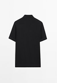 Polo shirt nera a maniche corte con colletto piatto, tessuto testurizzato, orlo dritto e senza loghi o dettagli visibili sul retro.