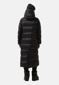 Schwarze Daunenjacke mit einem langen, gepolsterten Design und hohem Kragen. Sie verfügt über eine Kapuze mit Logo, einen Reißverschluss und Rippstrickakzente an der Mütze.