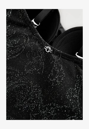 Must mustriga kangas, millel on sädelev ja tekstureeritud muster, hõbedase aktsendiga ja reguleeritavad mustad rihmad. Sisepind on sile.