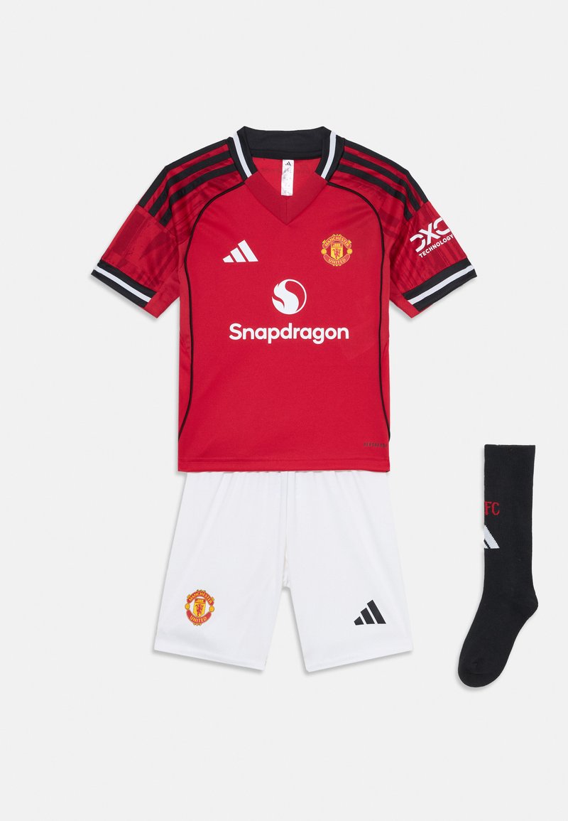 Maglia da calcio rossa con dettagli neri, caratterizzata da un logo e uno sponsor. Pantaloni bianchi con un emblema. Calzini neri con dettagli del logo.