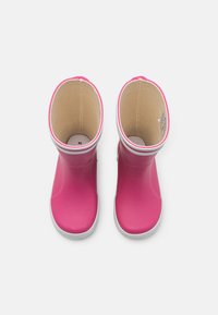 Bottes de pluie en caoutchouc rose avec une finition lisse, semelles blanches et un intérieur texturé. Comprend un bout rond et un revers surélevé.