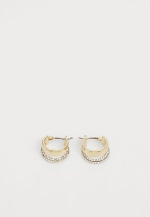 Kolczyki koła w złotym odcieniu z rzędami małych przezroczystych kryształów na zewnętrznej krawędzi, ułożonych obok siebie na białym tle.