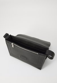 Borsa a tracolla nera in pelle con chiusura a zip, dotata di una tasca interna e di una tracolla regolabile. Texture liscia e design minimalista.