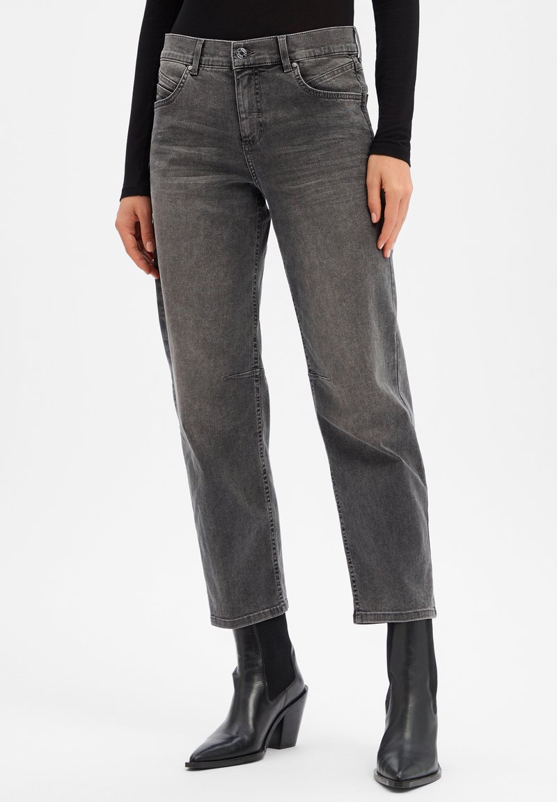 Jean en denim gris avec un design à jambes droites, cinq poches, un léger délavage et des coutures contrastées, associés à des bottines noires.