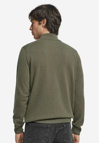 Sweter dziany w kolorze oliwkowej zieleni z kołnierzykiem, długimi rękawami i prążkowanym wykończeniem. Gładka faktura, dopasowany krój. Widok z tyłu ukazuje szwy na ramionach.