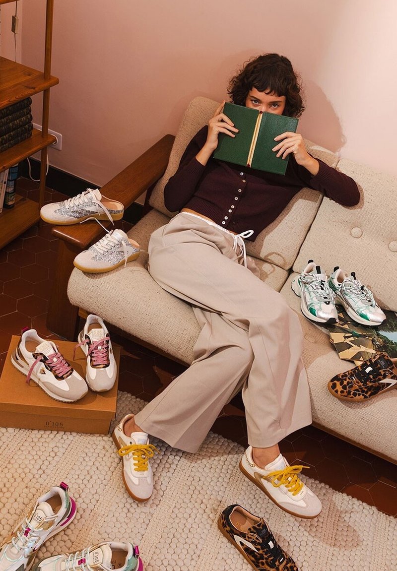 Sneaker alla moda in vari design: bianche con lacci rosa, beige con accenti argentati, stampa leopardata e verdi, disposte su un tappeto chiaro.
