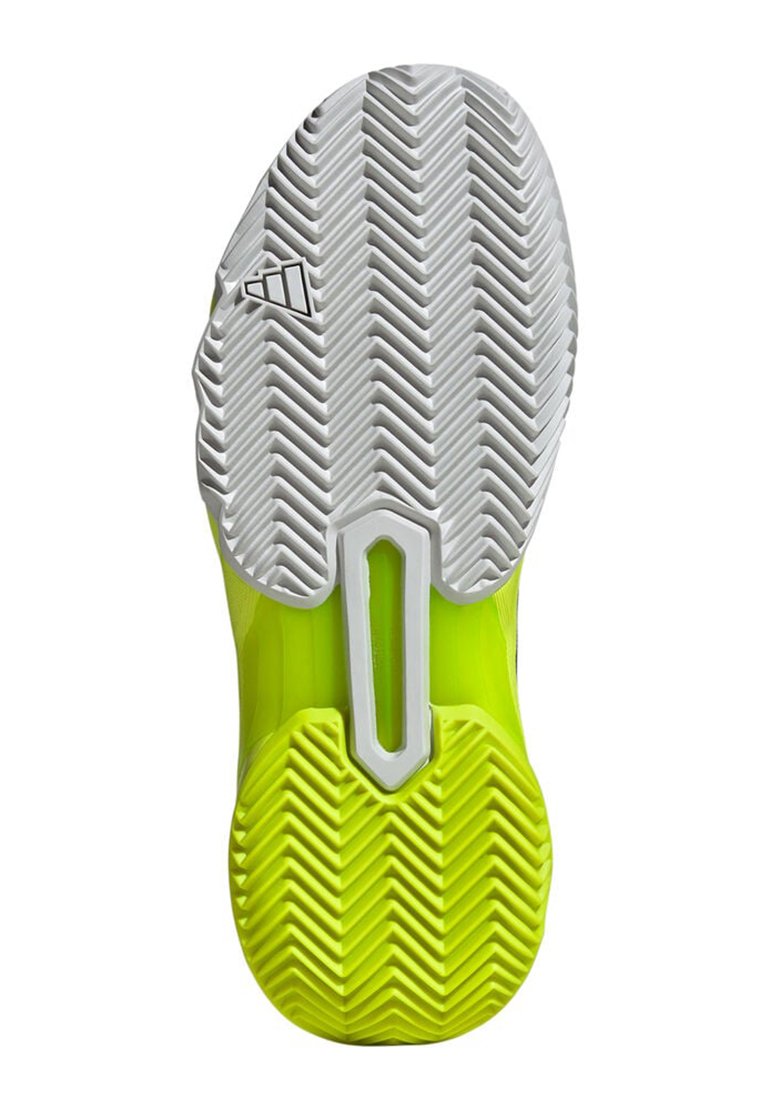 Suela de zapatilla deportiva con un diseño de goma blanca y amarilla neón. Presenta un patrón de espiga para tracción y recortes moldeados para reducir peso.