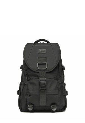 Černý batoh G-Star RAW s přední přezkou, horním kapsou na zip, bočními popruhy a madlem pro nošení na bílém pozadí.