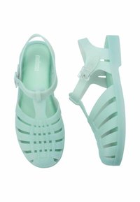 Miętowe sandały z żelatyny o otwartej, warstwowej konstrukcji, regulowanym pasku na kostce oraz teksturowanej wkładce. Wykonane z elastycznego, trwałego materiału.