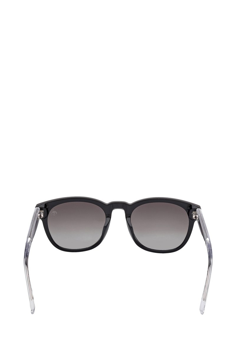 Schwarze Sonnenbrille mit dunkel verlaufenden Gläsern und durchsichtigen grauen Bügeln, gezeigt vor einem weißen Hintergrund.