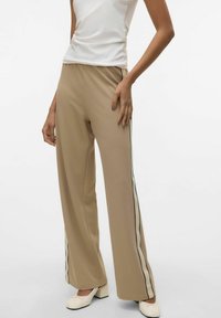 Beige wijde pijpen broek met contrasterende zwarte strepen langs de zijkanten, gemaakt van lichtgewicht stof, met een gladde textuur en een ontspannen pasvorm.