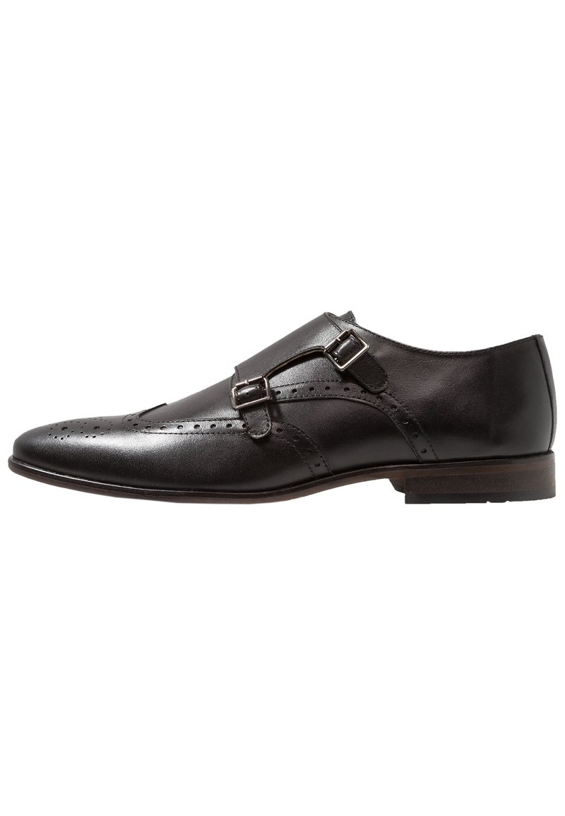 Svart läderskor med dubbla spännen, spetsig tå, dekorativ broguedetaljering och en platt träklack. Slät textur och elegant design.