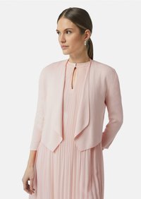 Helles rosa Cardigan mit offenem Design, langen Ärmeln und glatter Textur, übereinander getragen mit einem passenden gefalteten Kleid.
