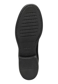 Suela de zapato de goma negra con superficie texturizada, que presenta estrías paralelas y perforaciones para la transpirabilidad. Logo grabado cerca del talón.