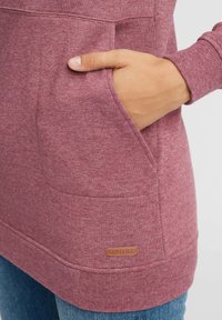 Mörkröd sweatshirt med en framficka, ribbade ärmslut och en läderlogotyp. Texturerad tyg med ett mjukt, avslappnat utseende.