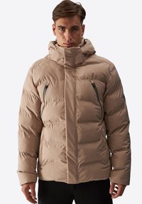 Beige pufferjakke med høj krave og hætte. Har to lynlåslommer og et glat, isoleret design. Tekstureret overflade synlig.