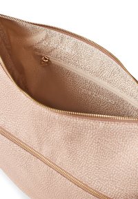 Light pink faux leather bag interior with a smooth texture, featuring a zippered pocket and a subtly patterned lining. Gold zipper hardware visible.
