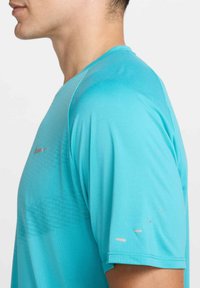 T-shirt atlético azul-claro feito de tecido suave, com mangas cortas, decote redondo e padrões texturizados subtis na parte superior do peito.