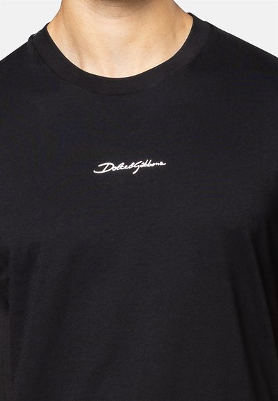 Zwarte katoenen t-shirt met ronde hals en korte mouwen. Beschikt over een klein wit "Dolce&Gabbana" logo op de borst. Gladde textuur.