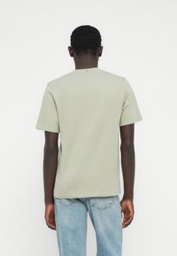 Ανοιχτό πράσινο κοντομάνικο μπλουζάκι με στρογγυλή λαιμόκοψη και ίσια τελειώματα. Κατασκευασμένο από βαμβάκι, διαθέτει διακριτική ραφή στη λαιμόκοψη.