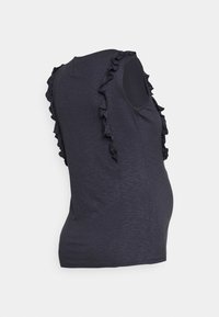 Grå linne med volangdetaljer längs axlarna, tillverkat av mjukt, lätt material, designad för att rymma en växande mage.