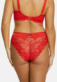 Ensemble de lingerie en dentelle rouge comprenant un soutien-gorge avec bretelles ajustables et une culotte assortie avec des motifs floraux et un détail entrecroisé à l'arrière.
