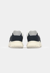 Navy sneakers featuring a white and grey heel accent, textured material, and a thick cream sole for enhanced cushioning and support.