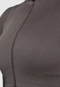 Donkergrijze geribbelde sporttop met een rits aan de voorkant, voorzien van textiel met structuur en een aansluitend ontwerp dat de vorm benadrukt.