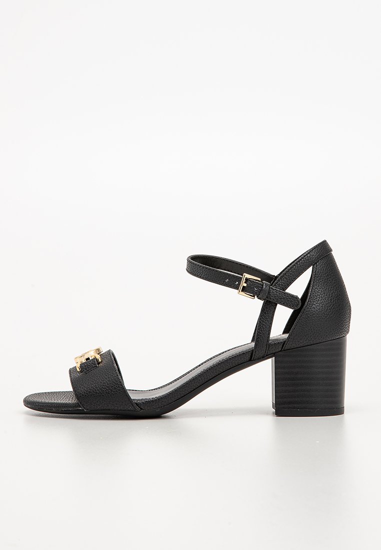 Sandales à talons en cuir noir avec une finition texturée, une sangle de cheville ajustable et une boucle décorative en métal doré à l'avant.