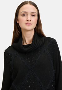 Zwarte gebreide sweater met een col, een diamanten patroon met subtiele glans en een fuzzy textuur langs de naden en accenten.