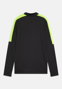 Langærmet skjorte, sort stof med neongrøn skulderpaneler, rund halsudskæring, glat tekstur og sideslids ved kanten.